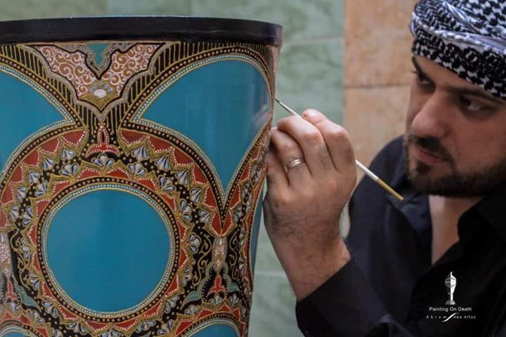 الفنان أكرم أبو الفوز خلال رسمه على مخلفات الحرب