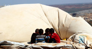 أطفال يجلسون على خيمتهم بعد أن هدمتها العاصفة الهوائية في مخيم كفتين بريف إدلب
