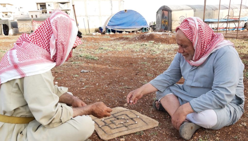 الحاج علي وخليل يلعبان الادريس بالقرب من خيمتهما -فوكس حلب