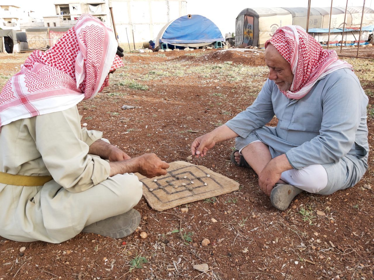 الحاج علي وخليل يلعبان الادريس بالقرب من خيمتهما -فوكس حلب