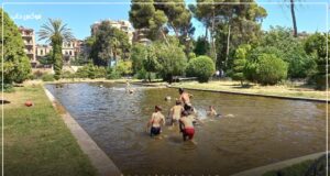 الصورة لأطفال يسبحون في بحرة داخل الحديقة العامة بحلب.