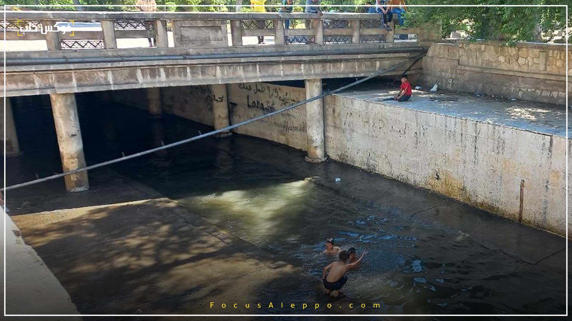 الصورة لأطفال يسبحون في مجرى نهر قويق بحلب.
