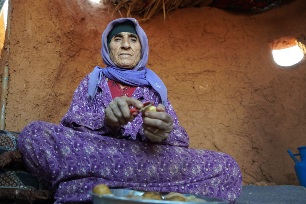 أمينة الخليف تُحضّر الطعام لأحفادها بجوار جدار طينيّ من إنشائهم. سرجبلة 2024 -تصوير: سحر زعتور