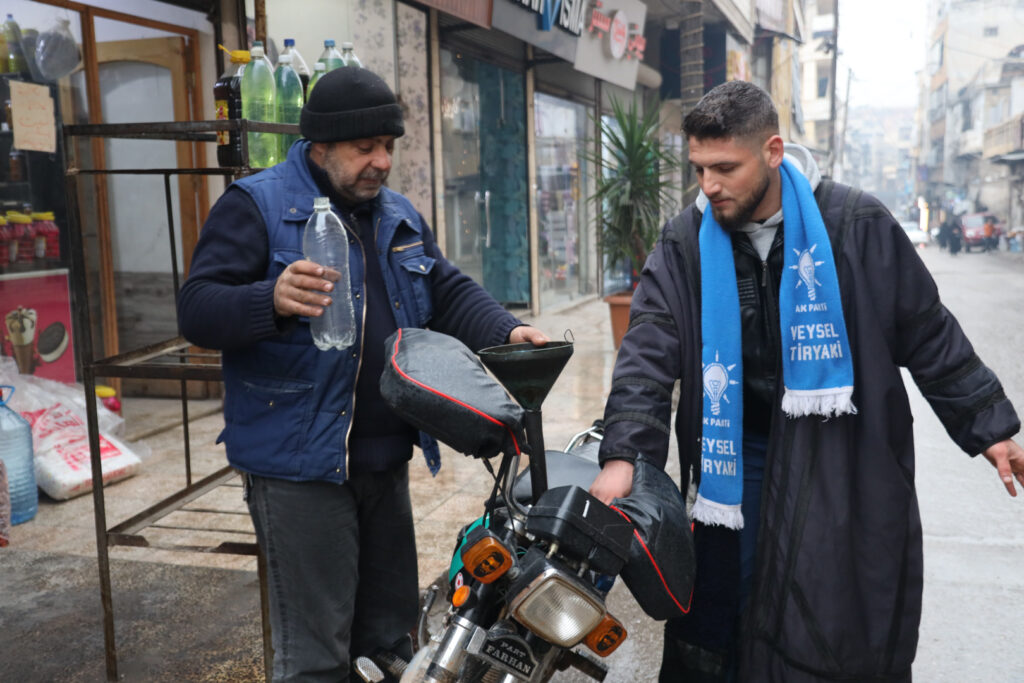 أحمد عثمان، يبيع البنزين لأحد الزبائن، مدينة كفرتخاريم غربي إدلب، شباط 2025- تصوير: رهام علي.