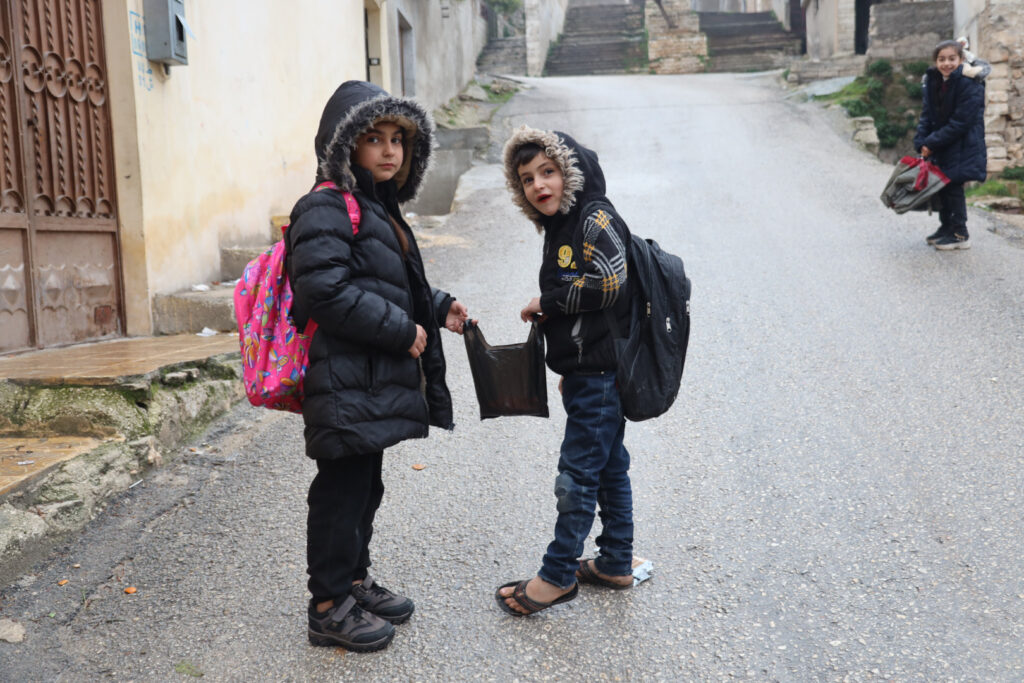 طفلان يتيمان أثناء عودتهما من المدرسة،مدية كفرتخاريم غربي إدلب، شباط 2025- تصوير: رهام علي.