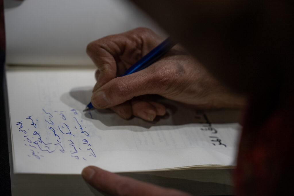 الكاتبة حسيبة عبد الرحمن توقّع نسخًا من روايتها "السماق المرّ" خلال حفل إطلاقها في مقهى الروضة وسط دمشق، نيسان 2025- تصوير: رؤى القصير
