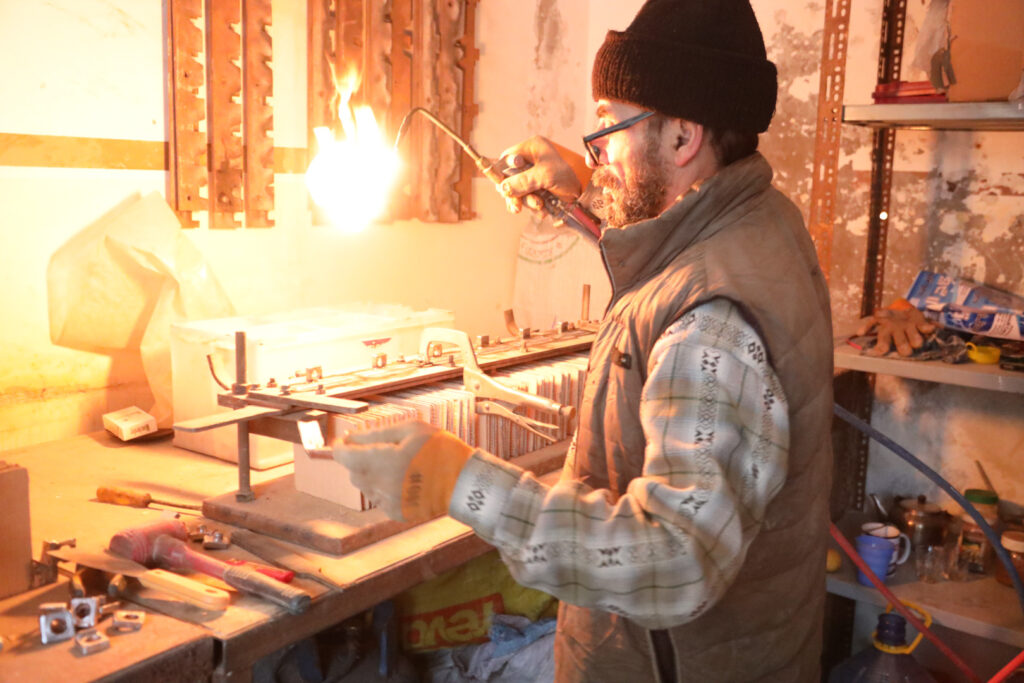  إياد الموصللي، يصنّع يدويًا بطاريات لادخار الطاقة، مدينة كفرتخاريم غربي إدلب، شباط 2025- تصوير: رهام علي.