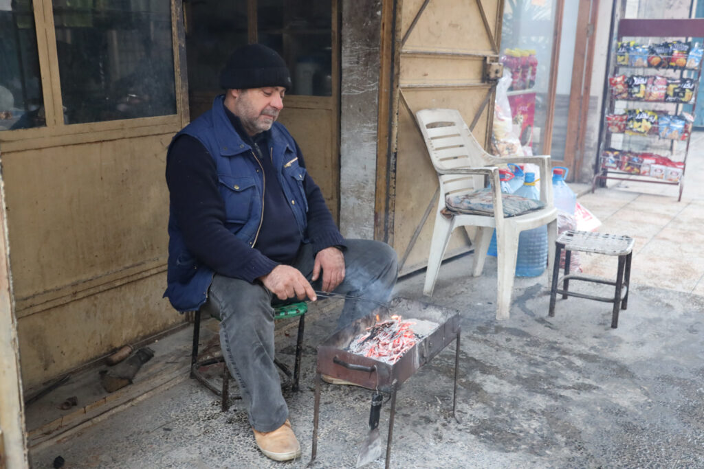 أحمد عثمان، معتقل سابق، أمام محله الذي يبيع فيه الوقود ومواد التدفئة، مدينة  كفرتخاريم غربي إدلب، شباط 2025- تصوير: رهام علي.
