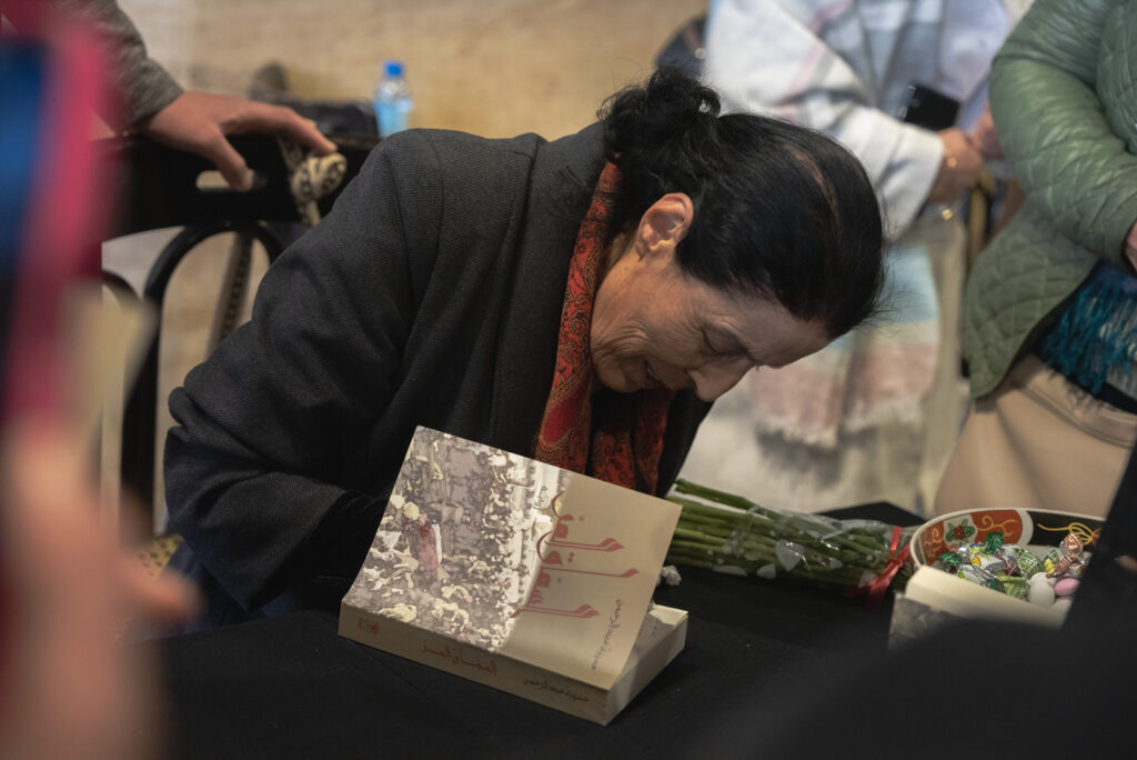 الكاتبة حسيبة عبد الرحمن توقّع نسخًا من روايتها "السماق المرّ" خلال حفل إطلاقها في مقهى الروضة الشهير وسط العاصمة، دمشق، نيسان 2025- تصوير: رؤى القصير