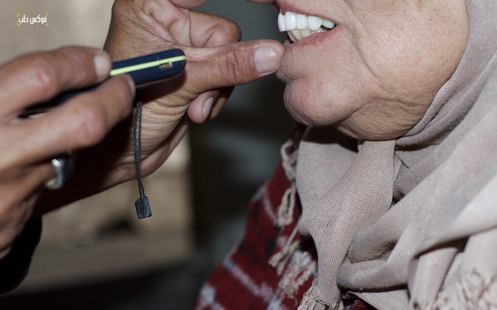 أبو حبيب اثناء تركيبه بدلة اسنان لسيدة في مدينة دير الزور، أيار 2025.