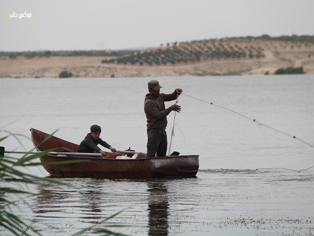 الصياد محمد أبو يونس وأبنه، بحيرة سد الساجور في ريف حلب الشرقي، أيار 2025.