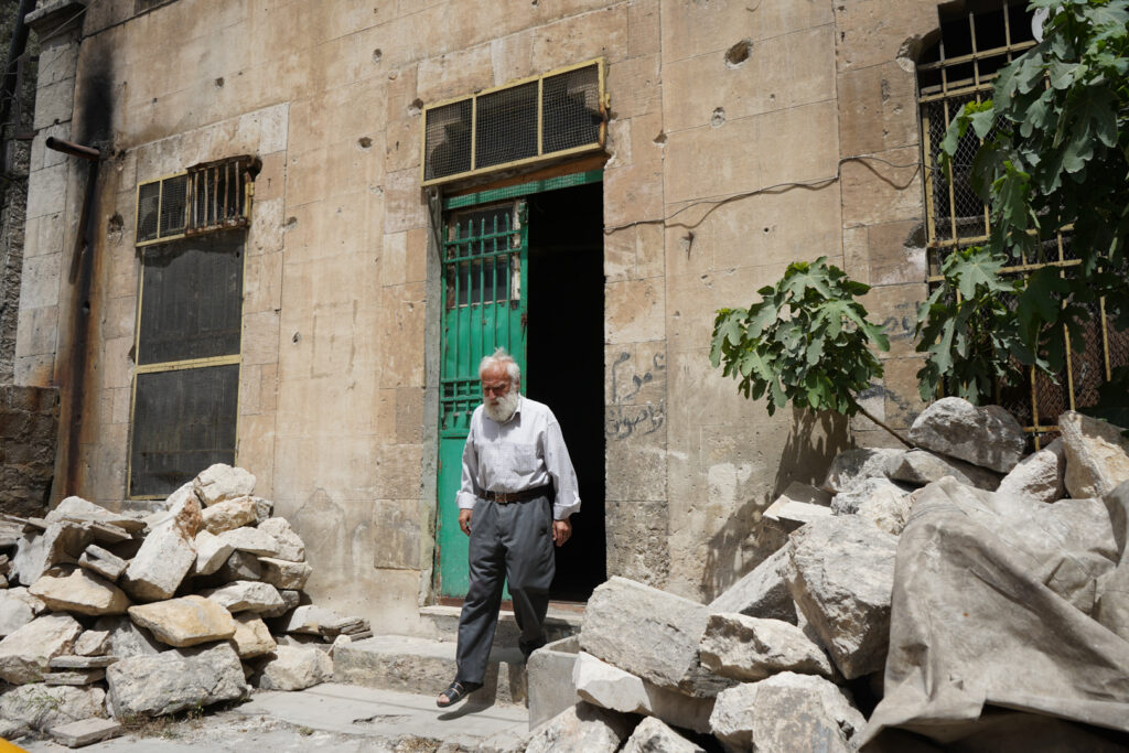 أبو عمر يخرج ليتفقد السيارات المركونة أمام منزله، حي الشعار في مدينة حلب، 2025- تصوير: سحر زعتور.