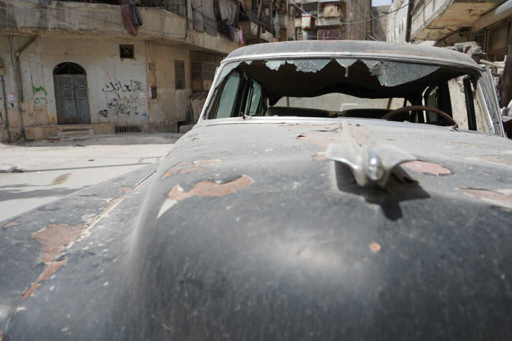 سيارة مركونة أمام منزل أبي عمر طالها القصف سابقًا، حي الشعار في مدينة حلب، 2025- تصوير: سحر زعتور.