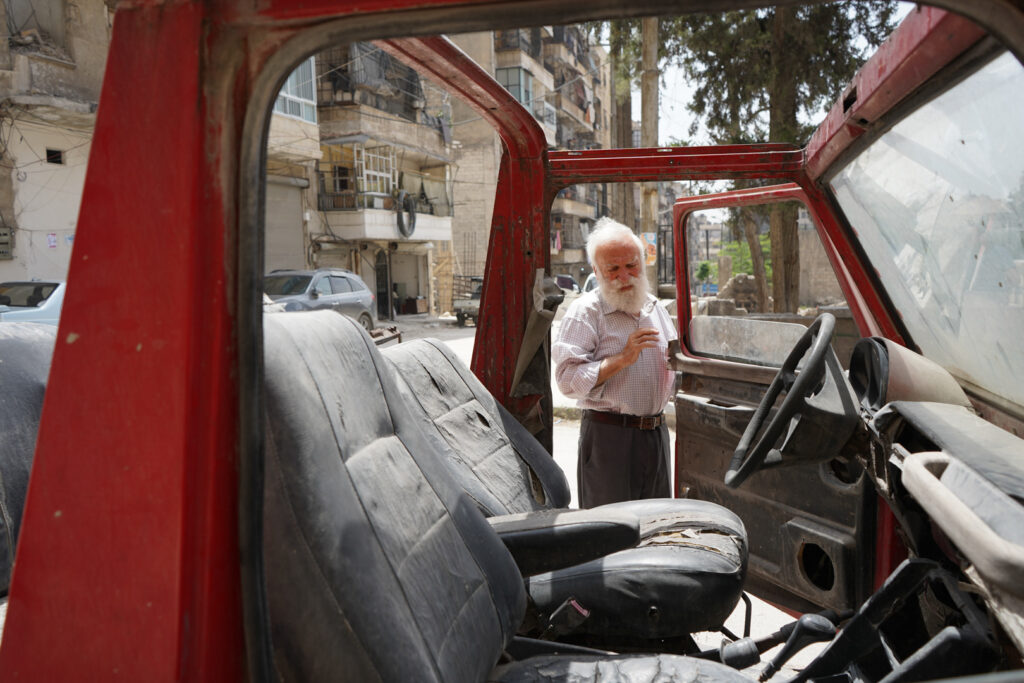 أبو عمر يقف أمام سيارة المرسيدس الرياضية موديل 1947، حي الشعار في مدينة حلب، 2025- تصوير: سحر زعتور.
