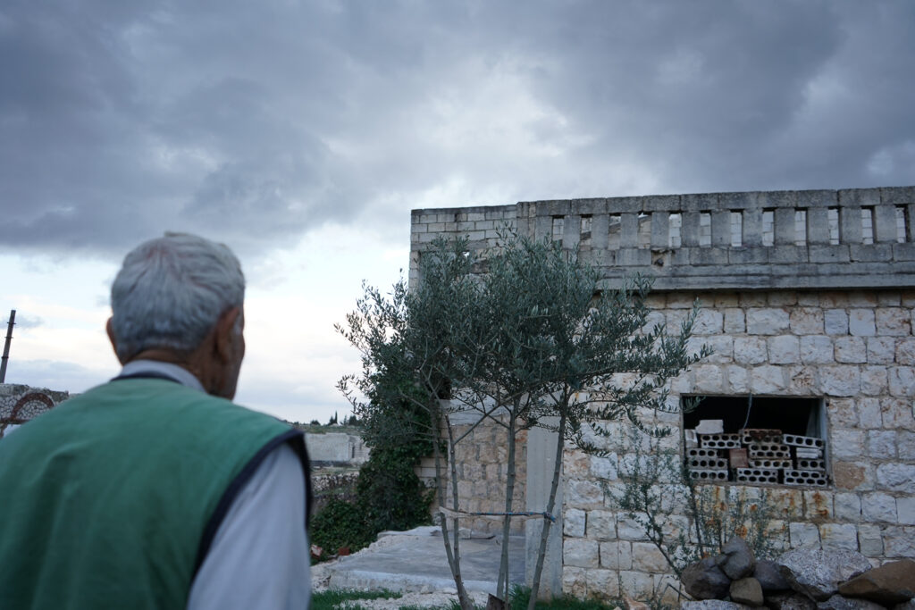 أبو محمد يتفقد النافذة التي أغلقها بالبلوك لمنع دخول الحيوانات إلى البيت أثناء النوم، كفرنبل، ريف إدلب، أيار 2025- تصوير: سحر زعتور