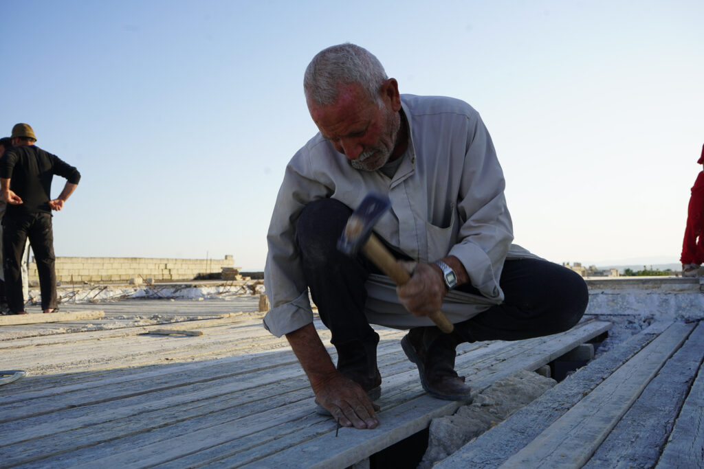 أبو محمد يثبت قالب الخشب استعدادًا لصب السقف، كفرنبل، ريف إدلب، أيار 2025- تصوير: سحر زعتور