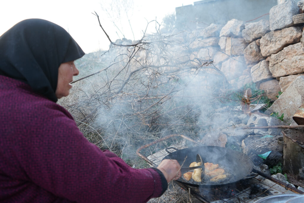 رغم حرارة الجو، أم محمد تقلي السمبوسك على النار لإطعام عائلتها، كفرنبل، ريف إدلب، أيار 2025- تصوير: سحر زعتور

