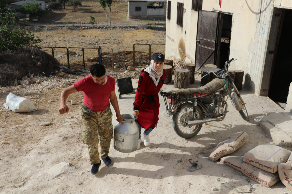 حلوم ووالدها يحملان جرة الحليب من مربي الأبقار.  قرية مشمشان، جسر الشغور، أيار 2025- تصوير: هيام الباشا 
