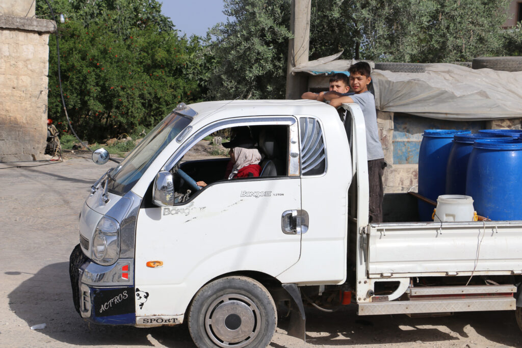 حلوم ووالدها ومعهم أحمد وعدنان العاملين في المعمل، في طريقهم لجمع الحليب.  قرية مشمشان، جسر الشغور، أيار 2025- تصوير: هيام الباشا 
