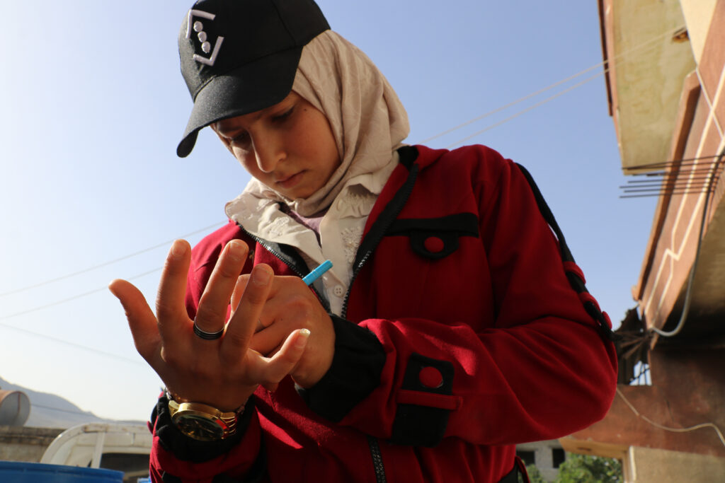 حلوم تسجل وزن الحليب على كفها لتكتبه على دفتر الحسابات بعد الانتهاء من تحميل الحليب.  قرية مشمشان، جسر الشغور، أيار 2025- تصوير: هيام الباشا