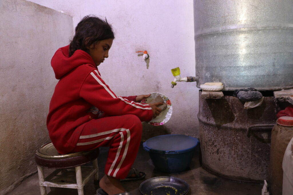 لميس، حفيدة أبي محمود تساعد جدها بالواجبات المنزلية. خربة الجوز، ريف جسر الشغور، تشرين الأول 2025. تصوير: هيام الباشا